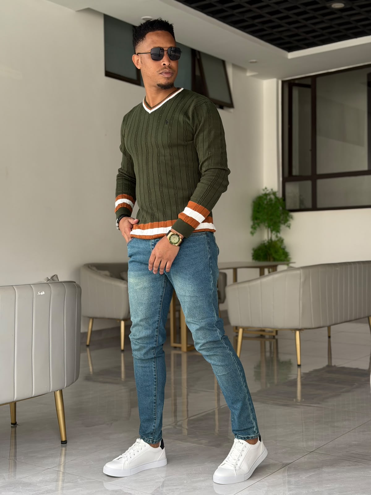 Slim-fit mid-wash blue jeans paired with an olive green sweater.